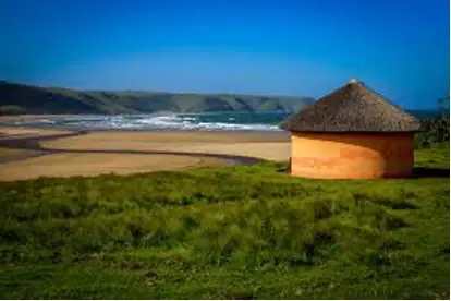 A hut on the beach with water in background.